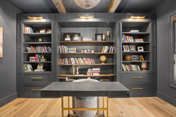 A home office space with charcoal and natural wood finishes and a feature wall of built-in shelving.