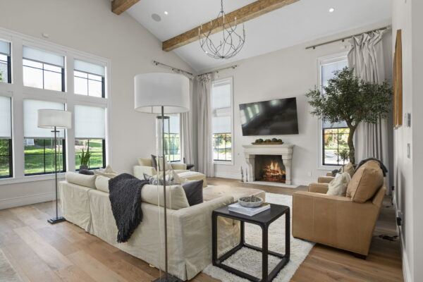 Armchairs, a sofa, and a chaise lounge positioned around a fireplace in a room with neutral finishes and ample natural light.