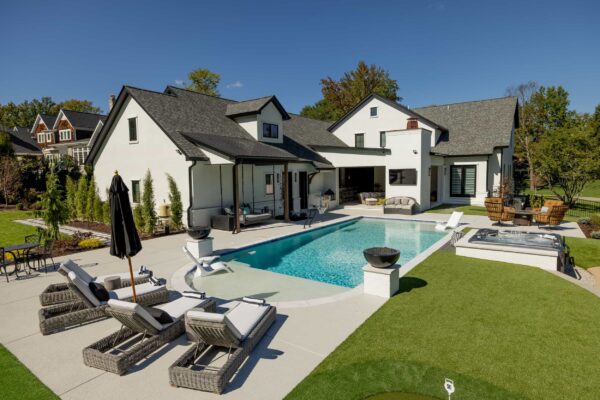 A manicured lawn featuring an in-ground pool, a hot tub, and multiple seating groups.