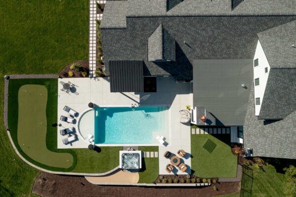 Aerial view of a manicured lawn featuring an in-ground pool, a hot tub, and multiple seating groups.
