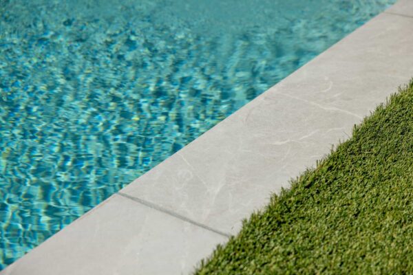 A manicured lawn transitions into a pool with a stone trim.