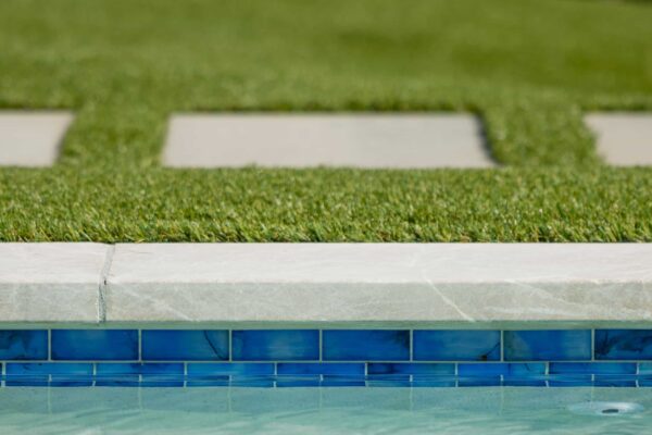 A manicured lawn transitions into a pool with a stone trim.