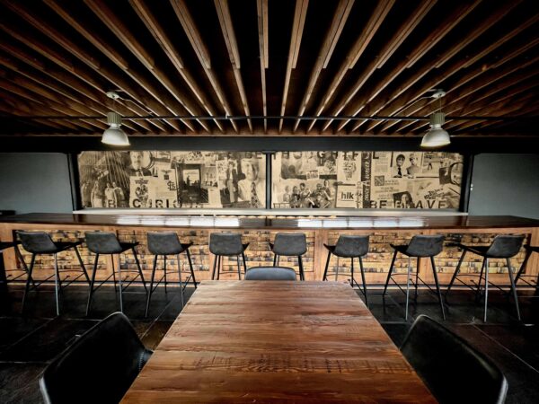 A bar area with wood and dark charcoal finishes in a room with an exposed ceiling.