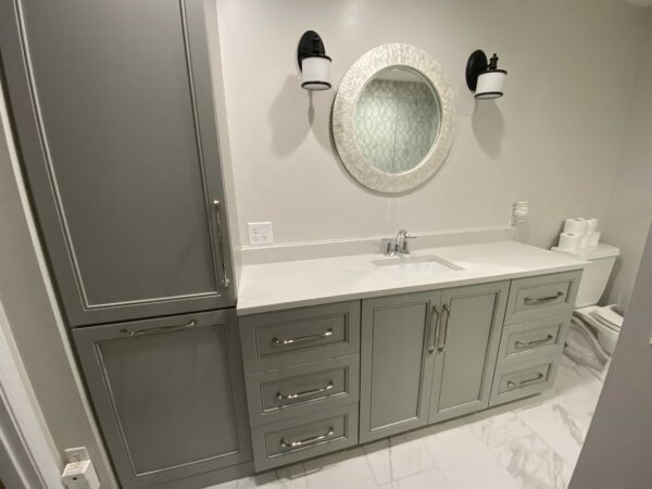 A single vanity with a white stone countertop and gray cabinets.
