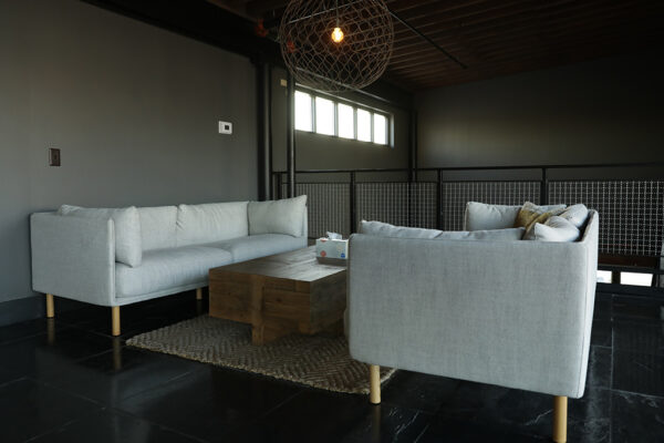 Sofas upholstered in a light-colored fabric and supported by wooden cylinder legs are positioned on either side of a wood coffee table.