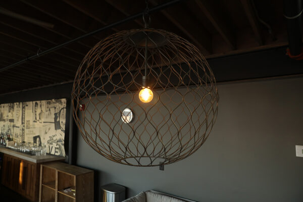A large wire globe pendant with an exposed light bulb.