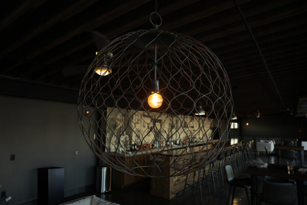 A large wire globe pendant with an exposed light bulb.