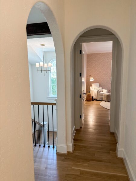 A hallway with arched doorways and oak flooring.
