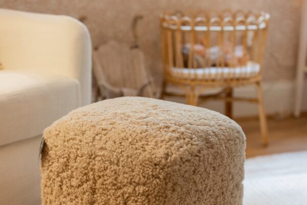 A neutral shearling ottoman in a child's room.
