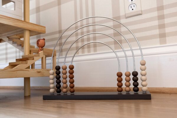 A rainbow-shaped abacus with wooden beads in a child's room.