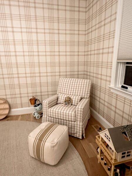 An armchair upholstered in neutral plaid fabric in a room with neutral plaid wallpaper.