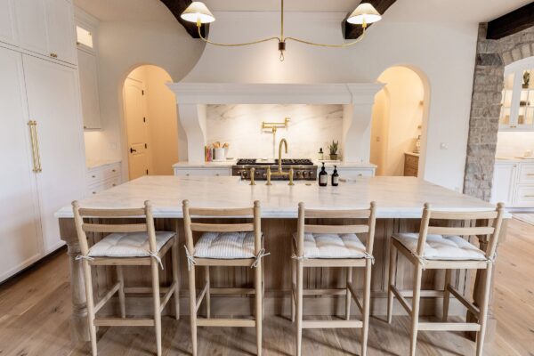 An oak island with a white marble countertop and four oak counter-height stools with removable striped cushions.