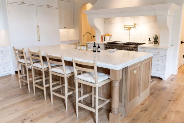 An oak island with a white marble countertop and four oak counter-height stools with removable cushions.