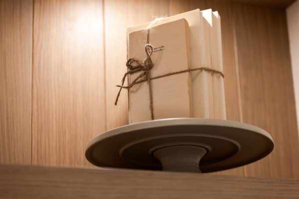 A stack of vintage books tied together with twine stands on an elevated circular tray.