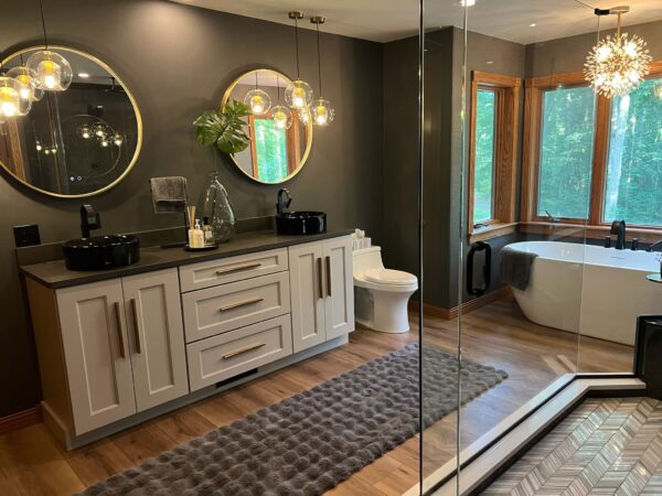 Bathroom with charcoal walls, freestanding tub, glass shower with herringbone tile and black vessel sinks on a double shaker vanity.
