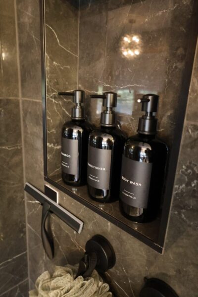 Modern recessed shower niche clad in dark grey marble with white veining.