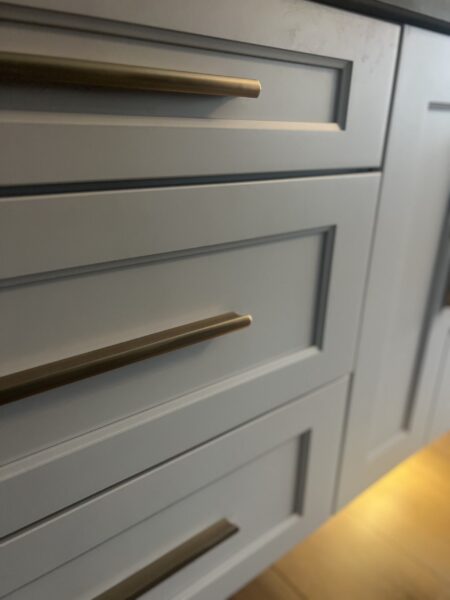 Detail view of a white shaker vanity with brass bar pulls.