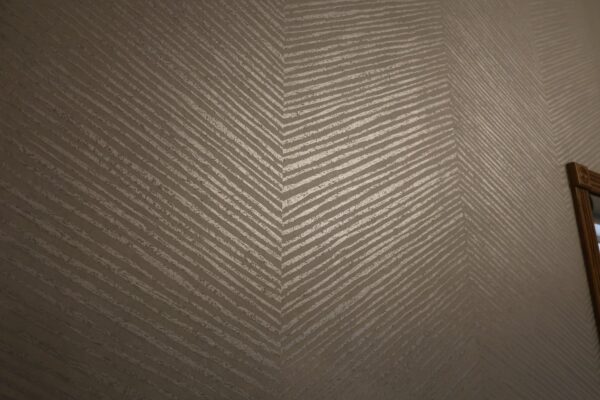 Taupe accent wall with textured geometric chevron stripes.